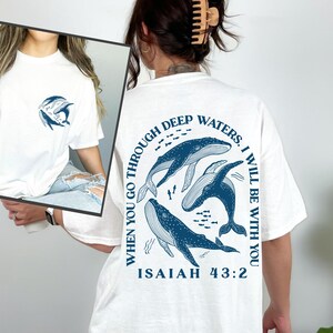 May include: White t-shirt with a blue graphic of whales and the text "WHEN YOU GO THROUGH DEEP WATERS. I WILL BE WITH YOU ISAIAH 43:2"