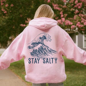 May include: Pink hoodie with a blue wave graphic and the text "STAY SALTY" on the back.