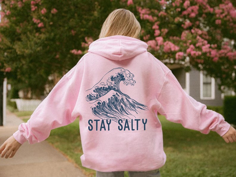 May include: Pink hoodie with a blue wave graphic and the text "STAY SALTY" on the back.