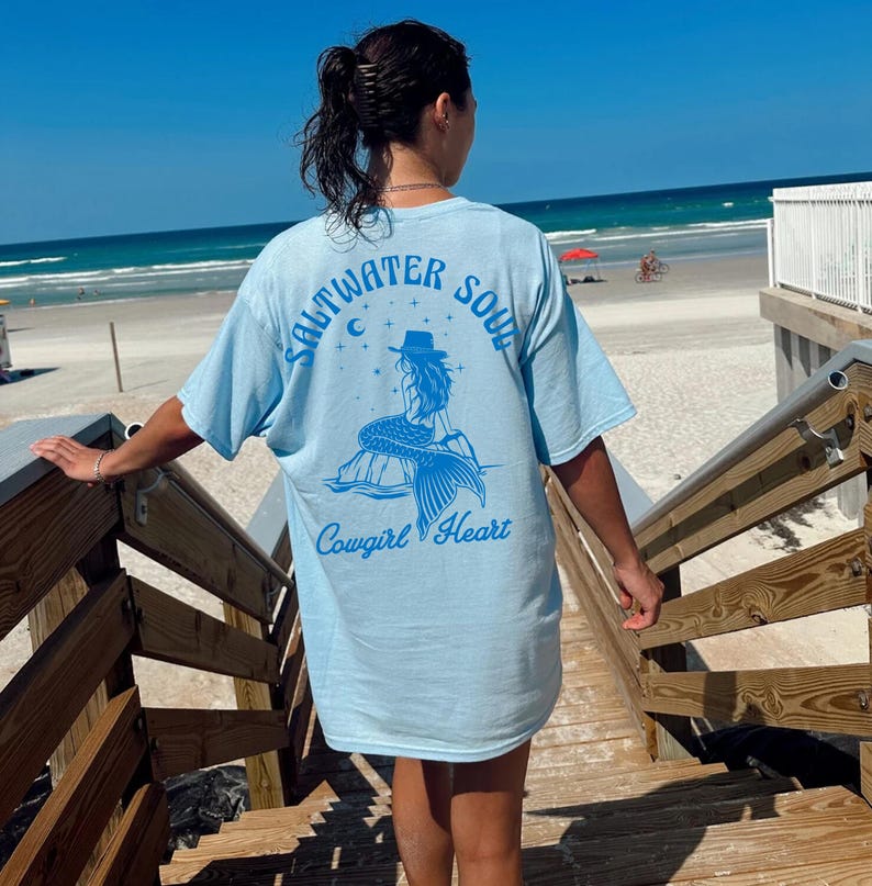 Peut inclure: T-shirt bleu clair avec un graphique de sir&egrave;ne et le texte "Saltwater Soul Cowgirl Heart".