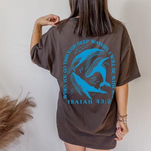 May include: Brown t-shirt with a blue graphic of whales and the text "When you go through deep waters, I will be with you" and "Isaiah 43:2".