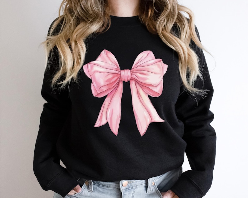 May include: A black sweatshirt with a large pink bow printed on the front.