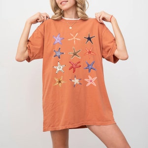 May include: A rust-colored oversized t-shirt with a graphic print of 12 different starfish in various colors and patterns.
