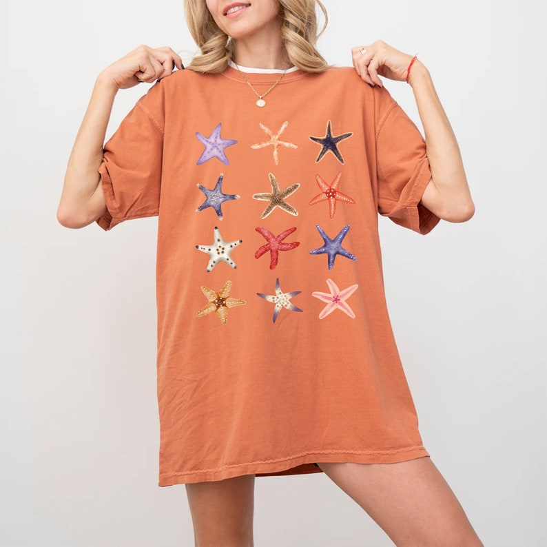 May include: A rust-colored oversized t-shirt with a graphic print of 12 different starfish in various colors and patterns.
