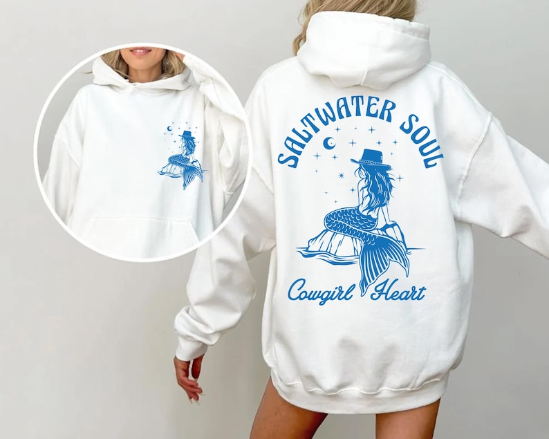 Peut inclure: Sweat-shirt blanc avec un graphique de sir&egrave;ne bleu et le texte "Saltwater Soul Cowgirl Heart" au dos.