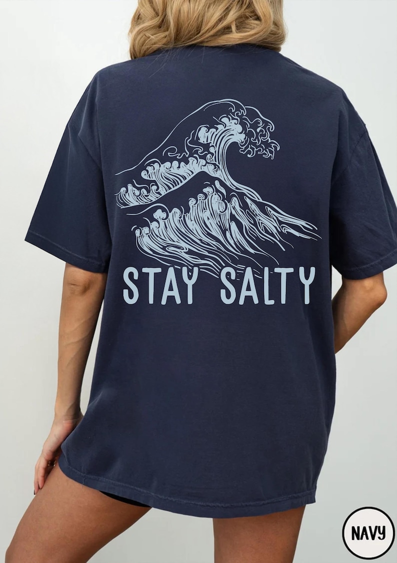 May include: A navy blue t-shirt with a graphic of a wave and the text "STAY SALTY" printed on the back.