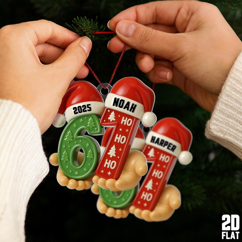 May include: Christmas ornaments in the shape of the numbers 6, 7, and 1, and a Santa hat. The ornaments are green and red with the names "Noah" and "Harper" and the year "2025" on them. The ornaments are being held by a person.