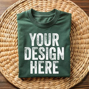 May include: A folded green t-shirt with the text "YOUR DESIGN HERE" printed in white on the front.