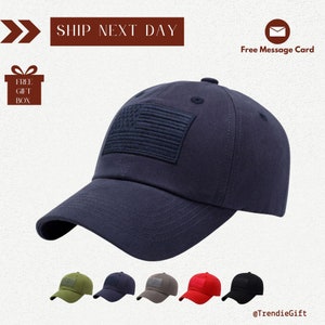 May include: A navy blue baseball cap with an embroidered American flag on the front. The cap has a curved brim and an adjustable strap.
