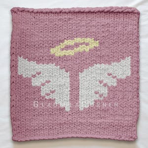 Op de afbeelding: Een vierkante, gebreide deken in een stoffige roze kleur. De deken heeft een wit engelen vleugelontwerp en een gele halo. De tekst "GLADIOLACORNER" is zichtbaar aan de onderkant. De deken is gemaakt van een dikke, grove brei.