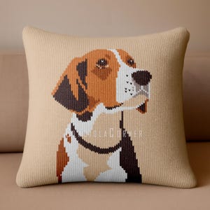 May include: Square beige cushion with a knitted texture, displaying a pixelated image of a dog's head. The dog has brown, white, and black markings, and a black collar. The text "@DIOLACORNER" is visible. The cushion is placed on a beige surface.
