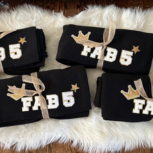 May include: Four black sweatshirts with gold crowns and stars, each with the text "FAB 5" in white letters.