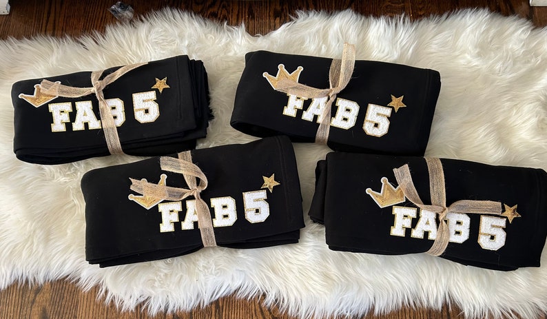 May include: Four black sweatshirts with gold crowns and stars, each with the text "FAB 5" in white letters.