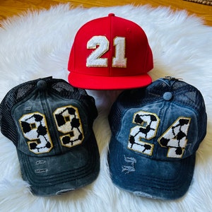 May include: Three baseball caps with distressed denim fabric and mesh panels. The caps feature a soccer ball design with numbers 21, 99, and 24.