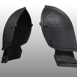Könnte beinhalten: Zweiteilige, dunkelgraue Metallrüstung, möglicherweise Schulterpanzer, mit strukturierter Oberfläche. Die Rüstung hat eine gebogene Form und scheint zum Schutz bestimmt zu sein. Das Design deutet auf ein historisches oder Fantasy-Thema hin.