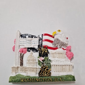 Puede incluir: Imán de recuerdo 3D blanco, rojo y azul con un águila calva, el Monumento a Washington, la Casa Blanca, el Capitolio y flores de cerezo. El imán dice "WASHINGTON, D.C."