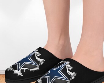 Pode incluir: Chinelos pretos sem cadarços com o logotipo da estrela do Dallas Cowboys em azul e branco. O logotipo parece estar rompendo um efeito de metal rasgado. Os chinelos têm uma sola preta e um design confortável.