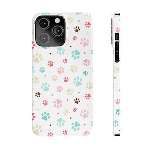 May include: A white phone case with a pattern of colorful paw prints. The case is designed for an iPhone 13 Pro Max.