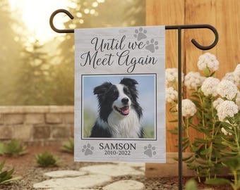May include: A memorial garden flag featuring a black and white dog portrait with the text "Until we Meet Again." The flag includes the dog's name, "Samson," and dates, 2010-2022, with paw print accents. The flag is displayed on a black metal stand.