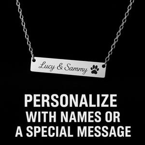 Puede incluir: Un collar de barra plateada con los nombres "Lucy & Sammy" y una huella de pata. El collar cuelga de una cadena fina. La imagen también incluye el texto "PERSONALIZA CON NOMBRES O UN MENSAJE ESPECIAL" en blanco.