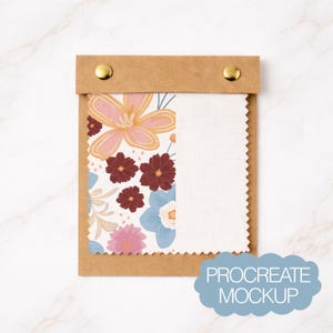 Op de afbeelding: Een bruine papieren stalenhouder met twee gouden klinknagels bevat twee stoffen stalen. Eén staal heeft een bloemenpatroon met roze, bordeauxrode en blauwe bloemen. De andere is effen witte stof. De tekst "PROCREATE MOCKUP" staat in een blauwe wolk.