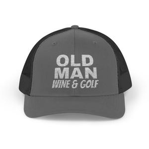 May include: A gray trucker hat with a black mesh back. The hat features the white text "OLD MAN WINE & GOLF" across the front. The hat has a curved brim and a snapback closure.