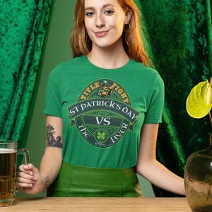 May include: A green t-shirt with a green, gold, and white graphic of a leprechaun holding a beer mug. The graphic says "Title Fight St. Patrick's Day vs. The Liver" with a shamrock and the date "March 17".