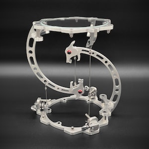 May include: A silver metal sculpture with a glass top and intricate moving parts. The sculpture is designed in the shape of an 'S' and features two red accents.