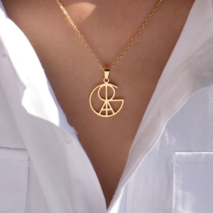 以下が含まれることがあります： 円の中に三角形と線が描かれた幾何学的なペンダントが付いたゴールドネックレス。ペンダントは繊細なチェーンに付いています。