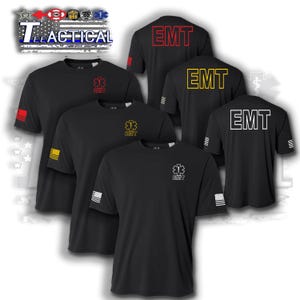 May include: Black short-sleeve T-shirts with "EMT" printed on the back in red, yellow, and white. Each shirt features the EMT symbol and the word "EMT" on the front. The shirts have a small American flag design on the sleeve.