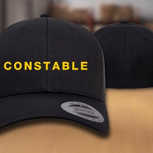 May include: Black and yellow trucker hat with the word "CONSTABLE" embroidered on the front.