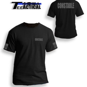 May include: Black t-shirt with the word "CONSTABLE" printed on the front and back. The shirt has a blue line on the sleeve and a small American flag on the sleeve.