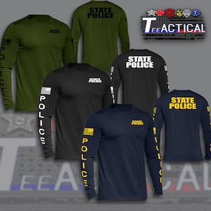 May include: Collection of long-sleeve shirts in various colors, including olive green, black, and navy blue. Each shirt features "STATE POLICE" text on the back and sleeve, with an American flag design. The brand name "Tee Tactical" is also visible.