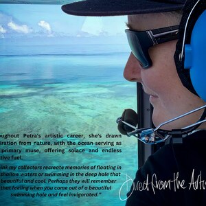 May include: A woman wearing sunglasses and a headset looks out the window of a helicopter. The view from the window shows a turquoise blue ocean with a bright blue sky above. The text "Direct from the Artist" is written in black cursive on the bottom right corner of the image.