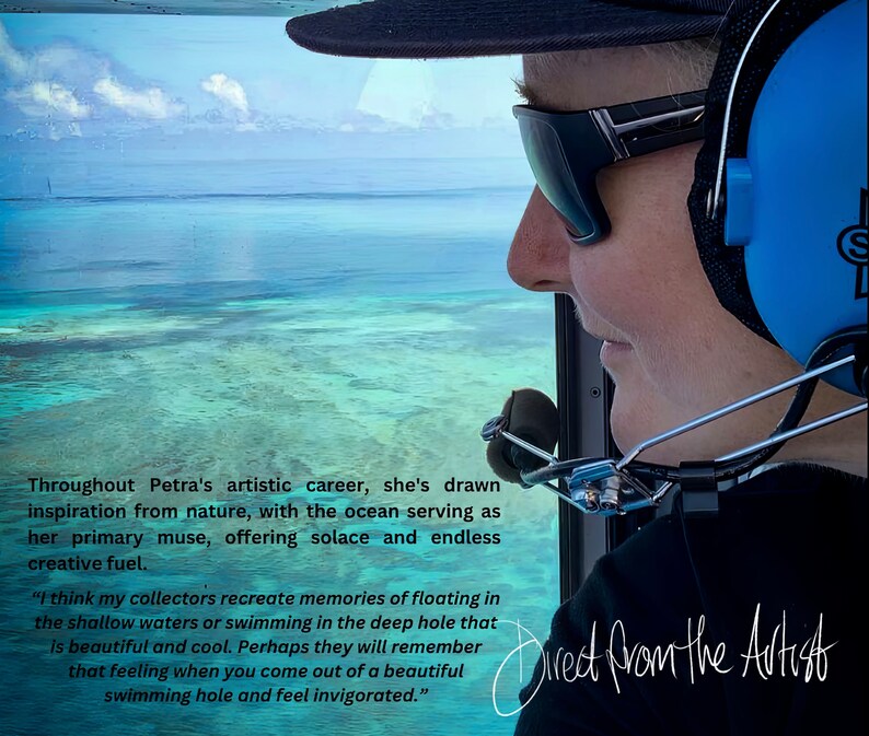 May include: A woman wearing sunglasses and a headset looks out the window of a helicopter. The view from the window shows a turquoise blue ocean with a bright blue sky above. The text "Direct from the Artist" is written in black cursive on the bottom right corner of the image.