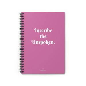 May include: Pink spiral bound notebook with the text "Inscribe the Unspoken." in white lettering. The notebook has a small logo at the bottom that says "stepping forward".