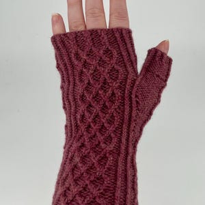 May include: A pair of maroon fingerless gloves with a cable knit pattern.