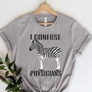 May include: Gray t-shirt with a black and white zebra illustration and the text "I CONFUSE PHYSICIANS".