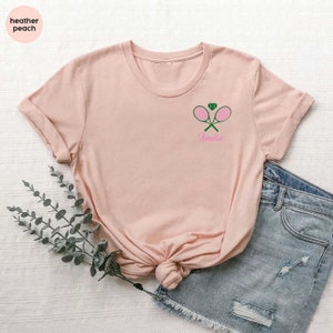 a pink shirt with a green tennis racket on it
