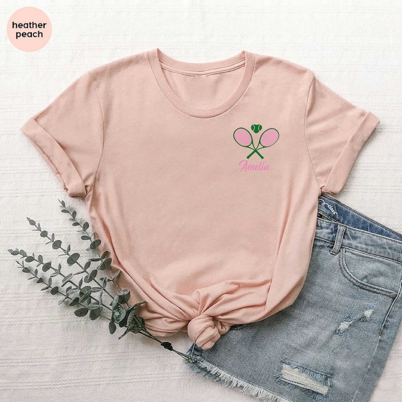 a pink shirt with a green tennis racket on it