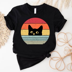 a black cat with yellow eyes on a black shirt