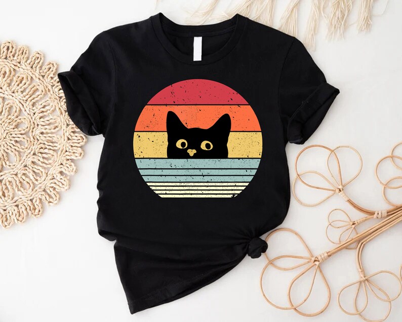 a black cat with yellow eyes on a black shirt