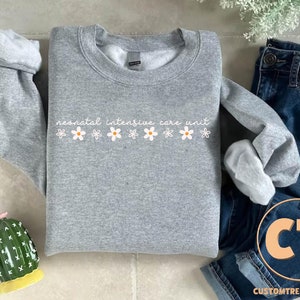 a sweater with flowers on it next to a cactus