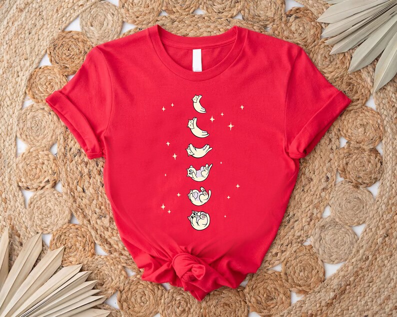 a red t - shirt with cats and the moon on it