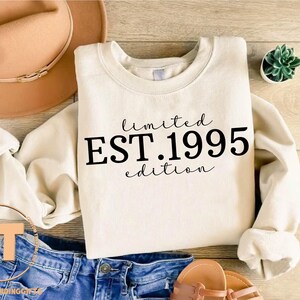 May include: A white crew neck sweatshirt with the text "limited EST.1995 edition" printed in black.