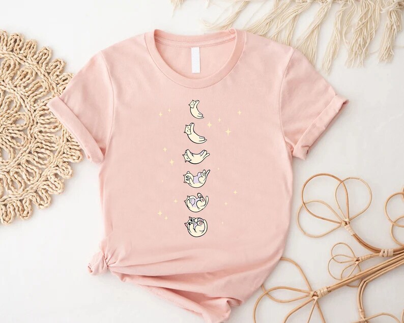 a pink t - shirt with cats and moon on it