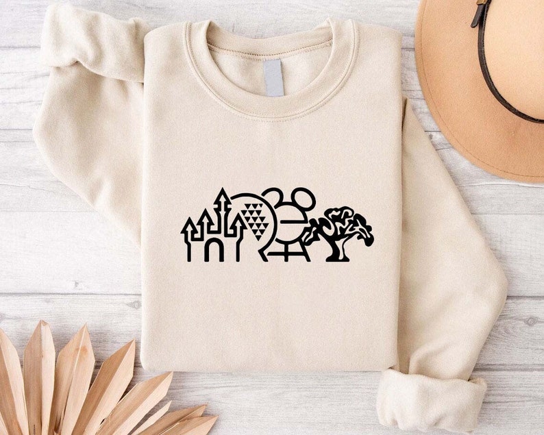 K&ouml;nnte beinhalten: Ein beiger Pullover mit einer schwarzen Grafik der ikonischen Disney World-Sehensw&uuml;rdigkeiten, darunter das Schloss von Aschenputtel, Spaceship Earth, der Mickey Mouse-Kopf und der Baum des Lebens.