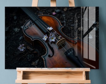 May include: A framed print of a violin with a warm brown finish, adorned with delicate purple and white flowers. The instrument rests on a dark surface, creating a contrast with the light-colored flowers. The print is displayed on a wooden easel.