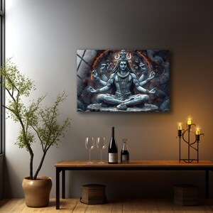 May include: A rectangular wall art print featuring a blue-toned depiction of a multi-armed deity in a meditative lotus position. The figure is surrounded by a glowing orange circular aura and intricate stone-like textures, set against a dark background.