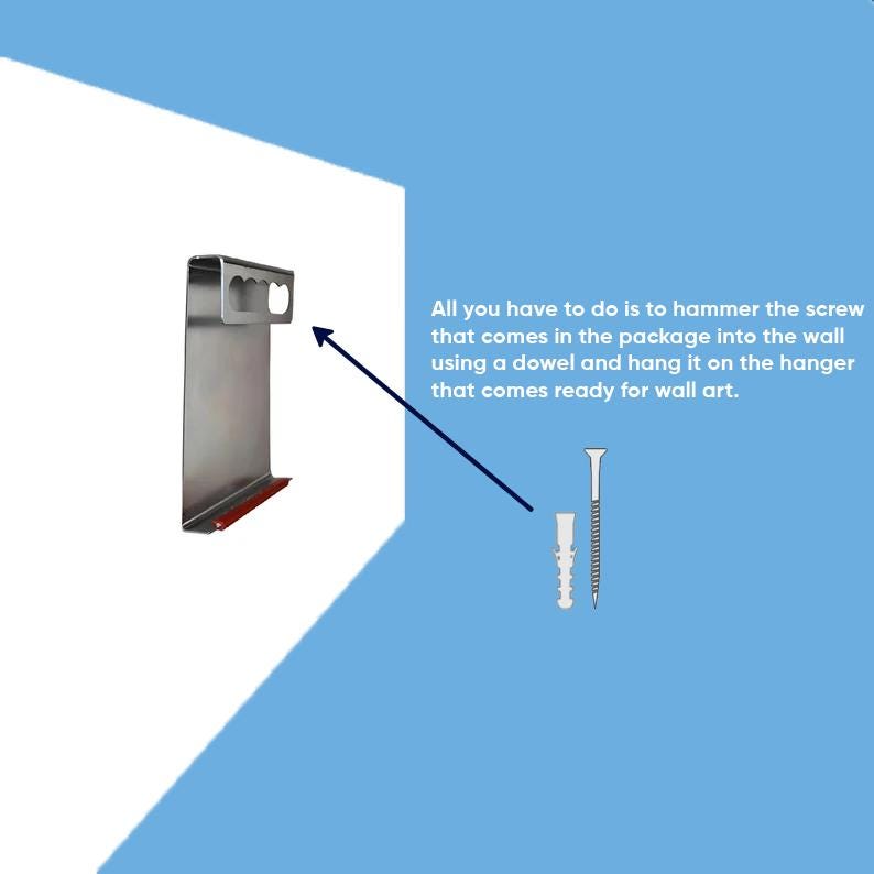 May include: A silver metal wall hanger with a rectangular top slot and a red bottom edge, accompanied by a wall screw and a plastic dowel. Text reads: All you have to do is to hammer the screw that comes in the package into the wall using a dowel and hang it on the hanger that comes ready for wall art.